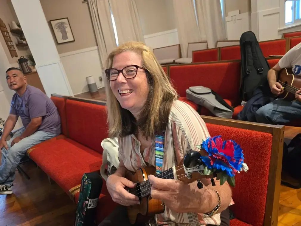 A player with a decorated ukulele at the front of the hall