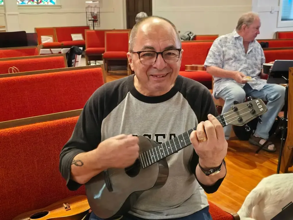 A player mid-song with a dark ukulele